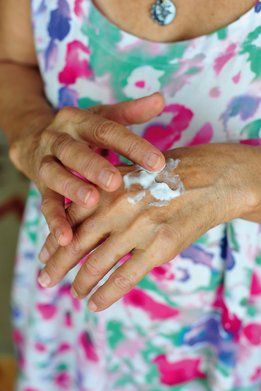 Vrouwenhanden die handcrème aanbrengen