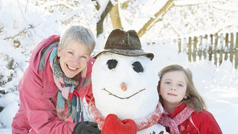 Grootmoeder en kleinkind maken een sneeuwpop