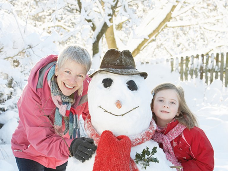 Grootmoeder en kleinkind maken een sneeuwpop