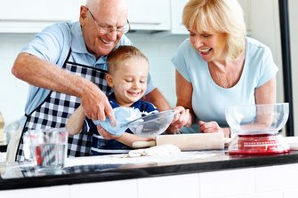 Ouder echtpaar en klein kind bereiden voedsel in de keuken